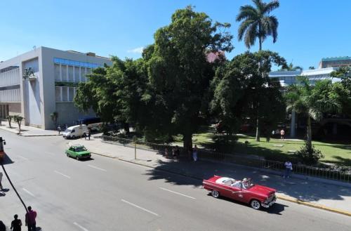 two old cars driving down a street next to a building at Casa Sayli Appartement 1 in Havana