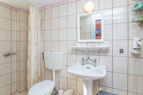 a bathroom with a sink and a toilet and a mirror at Minoa Hotel in Malia