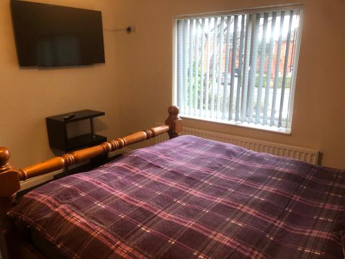 a bedroom with a bed with a plaid blanket and a window at Paula’s place 2 in Balby