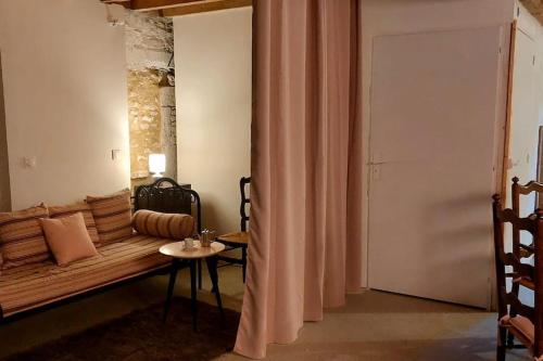 um quarto com um sofá, uma mesa e uma cortina em La Bergerie de Bénéauville 7 personnes em Bavent