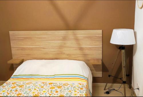 a bed with a wooden headboard next to a lamp at Les docks libres sud in Marseille
