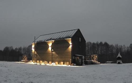 a wooden barn with lights on it in a field at Domek mazurski całoroczny nad jeziorem z Sauną fińską I Jacuzzi SPA in Pasym