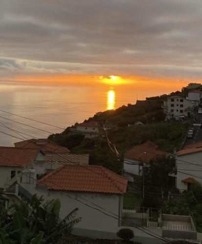 a sunset over the ocean with houses and buildings at Cozy 1 BR w/ balcony, ocean view & perfect sunsets in Ribeira Brava