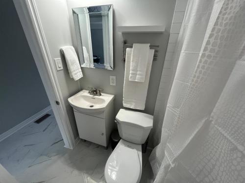 a white bathroom with a toilet and a sink at Casa LACK - Tranquila Suites 2 in Ottawa