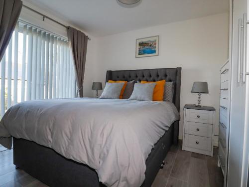 um quarto com uma cama grande e almofadas laranja em Palm View em Newquay