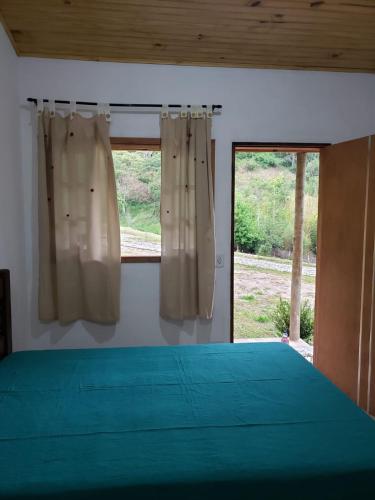 1 dormitorio con 1 cama y una ventana con cortinas en Chalézinho da Montanha - Sítio Pasangas, en Santo Antônio do Pinhal