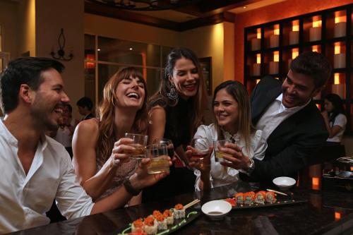 a group of people sitting at a bar with wine glasses at Real Intercontinental Metrocentro Managua by IHG in Managua