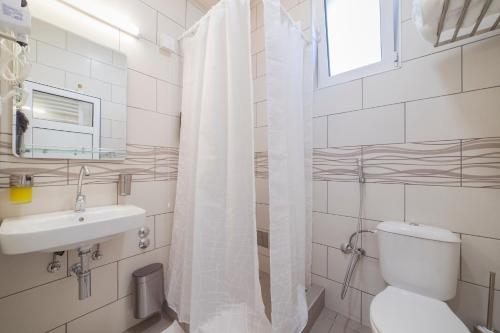 La salle de bains blanche est pourvue de toilettes et d'un lavabo. dans l'établissement AS APARTMANI PIROT, à Pirot