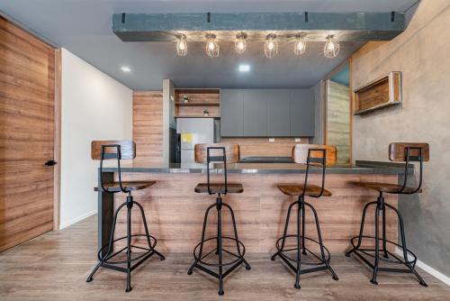 a kitchen with a bar with three stools at Olive Living Suites by HOUSY HOST in Envigado