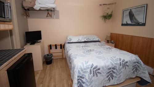a bedroom with a bed with a blue and white blanket at Les Cabines du Phare in Rimouski