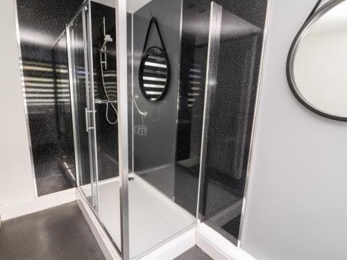 a shower with glass doors and a mirror in a bathroom at Mylnebeck Lodge in Windermere