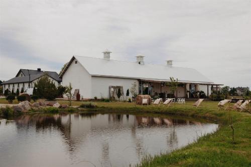une grande maison blanche avec un étang en face de celle-ci dans l'établissement Drwalski Zakątek, à Zatory
