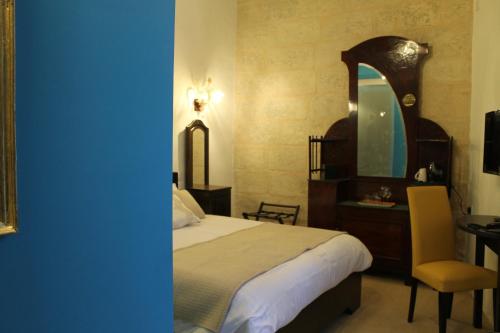 a bedroom with a bed and a desk and a mirror at Palazzino Nina Boutique Hotel in Qormi