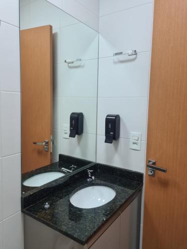 a bathroom with two sinks and a mirror at Studio Frente para o Mar - Matinhos in Matinhos