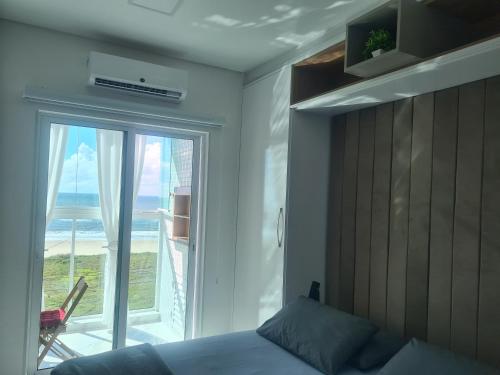 a bedroom with a bed and a view of the ocean at Studio Frente para o Mar - Matinhos in Matinhos