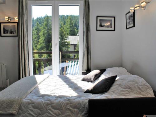 um quarto com uma cama e uma grande janela em Appartement Risoul, 1 pièce, 6 personnes - FR-1-330-506 em Risoul