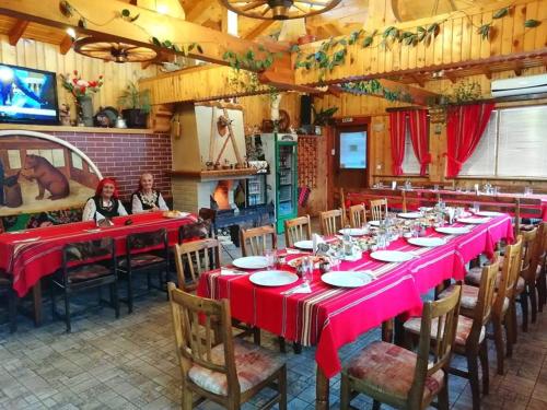 uma longa sala de jantar com mesas e cadeiras vermelhas em Kovacha Guest House em Raduil