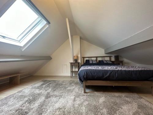 een slaapkamer op zolder met een bed en een raam bij Centre-ville f3 tout confort in Beaumont-sur-Oise