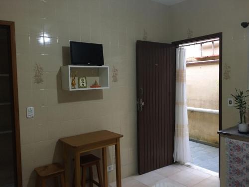 a room with a door with a television and a table at Chalés Maluí Ubatuba in Ubatuba