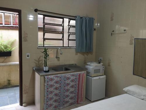a small kitchen with a sink and a microwave at Chalés Maluí Ubatuba in Ubatuba