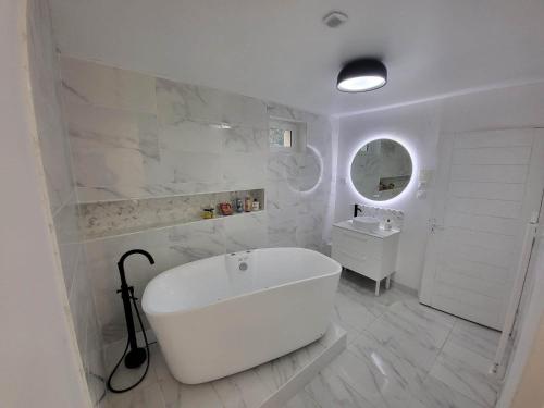a white bathroom with a tub and a sink at Gite des Rêves 