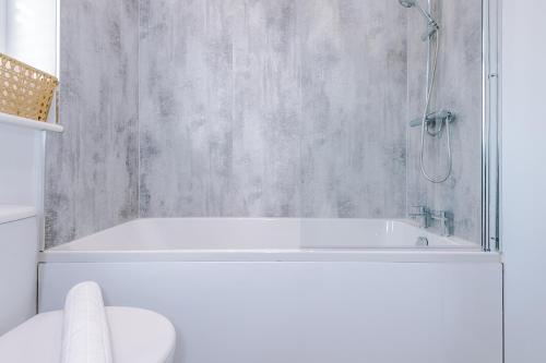 a white bathroom with a tub and a shower at Westwood Lodge Serviced Apartment in Coventry