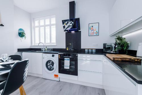 a white kitchen with a washer and dryer at Westwood Lodge Serviced Apartment in Coventry
