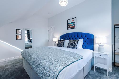 a bedroom with a blue bed and a mirror at Westwood Lodge Serviced Apartment in Coventry
