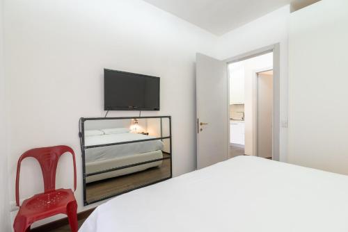 ペルージャにあるAppartamento Ponte Vecchioの白いベッドルーム(ベッド1台、赤い椅子付)