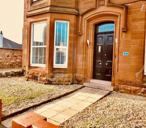 una casa con una puerta negra y una ventana en No 9 retreat, en Prestwick