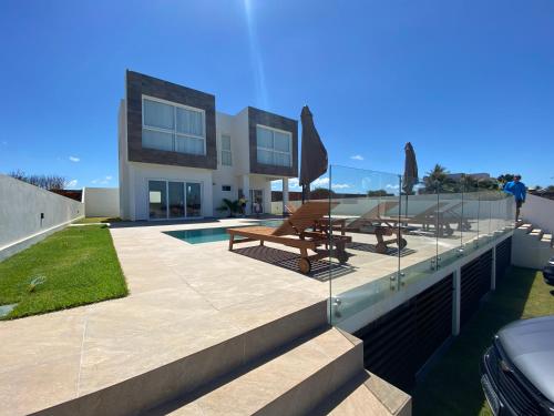 una casa con piscina y 2 bancos en PIPA Magnifique villa moderne en front de mer, en Tibau do Sul