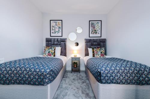1 dormitorio con 2 camas y mesa con lámpara en Hearsall Place Serviced Apartment en Coventry