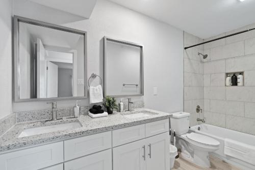 ein Badezimmer mit zwei Waschbecken, einem WC und einem Spiegel in der Unterkunft Evonify Stays - Highland - Stylish Furnished Apartments in Austin
