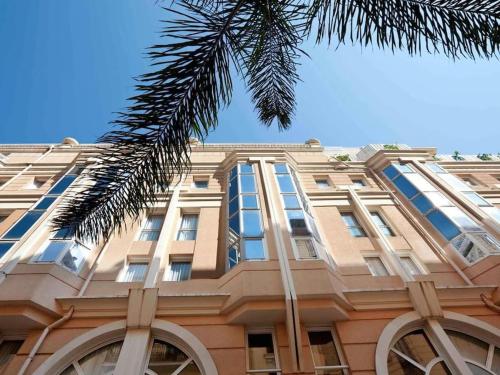 un bâtiment avec un palmier en face dans l'établissement Monaco Beausoleil "La maison de Marie", à Beausoleil