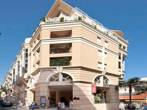 Un grand bâtiment avec des gens qui marchent devant lui dans l'établissement Monaco Beausoleil "La maison de Marie", à Beausoleil