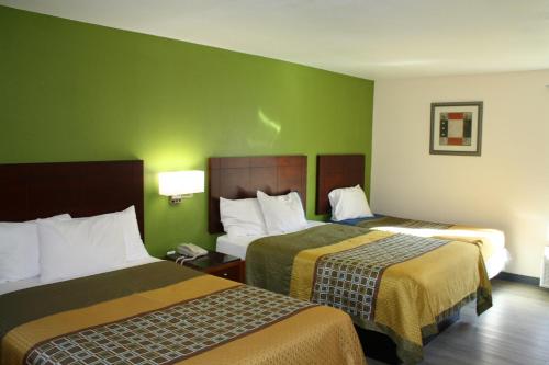 2 camas en una habitación de hotel con paredes verdes en Executive Inn and Suites Wichita Falls, en Wichita Falls