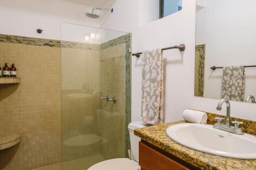 een badkamer met een wastafel, een douche en een toilet bij Beach Heaven in Playa Guiones