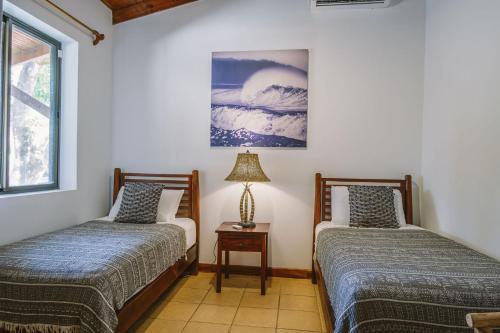 a bedroom with two beds and a lamp on a table at Beach Heaven in Playa Guiones