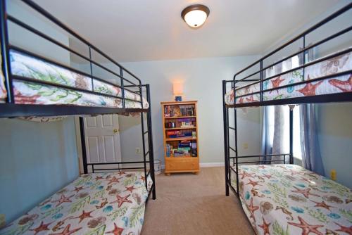ein Schlafzimmer mit 2 Etagenbetten und einem Bücherregal in der Unterkunft Barge Road 13609 home in Ocean City