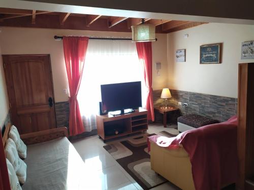 a living room with a television and red curtains at Departamentos Turísticos J&M en Dichato in Dichato