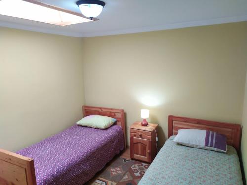 a bedroom with two beds and a table with a lamp at Departamentos Turísticos J&M en Dichato in Dichato