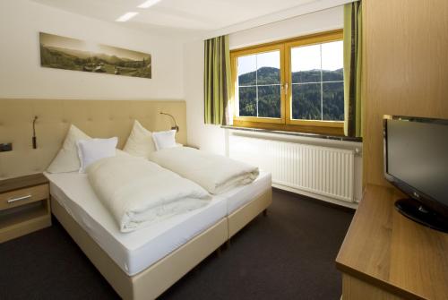 a bedroom with a bed with white pillows and a television at Haus Deiser in Kappl