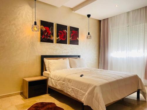 - une chambre avec un lit et deux photos sur le mur dans l'établissement A 2 minutes de Casa Finance City, appartement avec 2 Chambres, à Casablanca