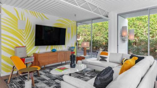 a living room with a couch and a tv on a wall at Limon Palm Springs A Luxury Boutique Hotel in Palm Springs
