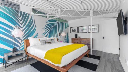 a bedroom with a bed with a yellow and white blanket at Limon Palm Springs A Luxury Boutique Hotel in Palm Springs