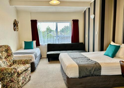 Habitación con 2 camas, sofá y silla en Parkside Motel and Apartments, en New Plymouth