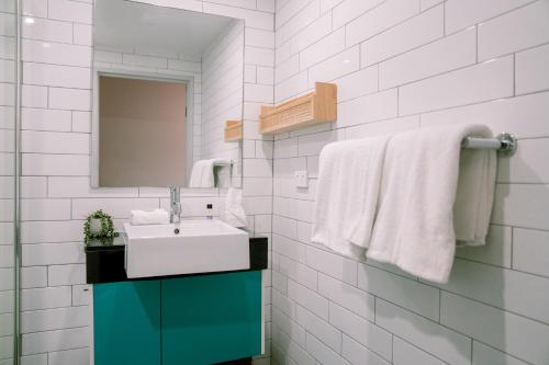 a bathroom with a sink and a mirror and towels at Vali Byron in Byron Bay