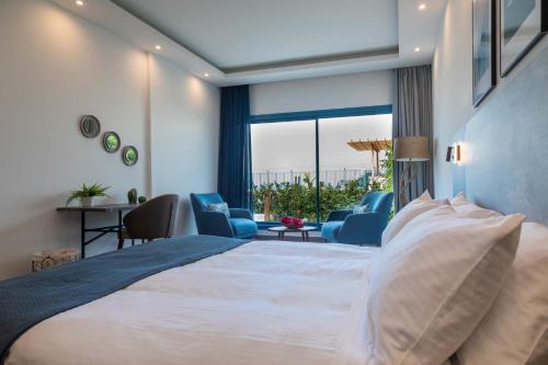 1 dormitorio con 1 cama blanca grande y sillas azules en The Lead Hotel en Freetown