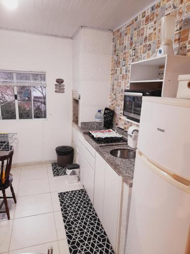 cocina con nevera blanca y fregadero en Lindo Flat em Maresias, en São Sebastião