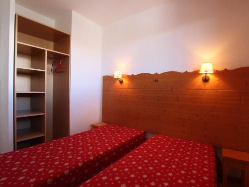 Appartement Puy-Saint-Vincent, 2 pièces, 6 personnes - FR-1-330G-76 في بوي-سانت-فينسينت: غرفة نوم بسرير احمر مع وجود مصباحين على الحائط